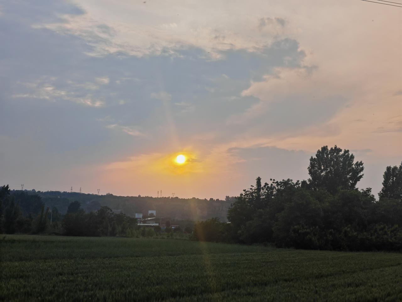 分享一张你拍的天空美照傍晚的田野里，夕阳正缓缓沉落，把天空染成一片暖黄与浅粉交织