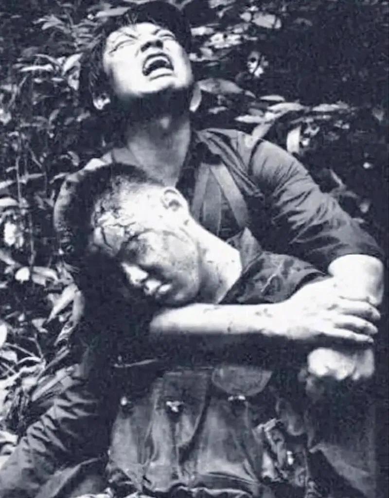 1984年，对越自卫反击战的211高地上，一名士兵头部中弹牺牲，他的战友抱着他的