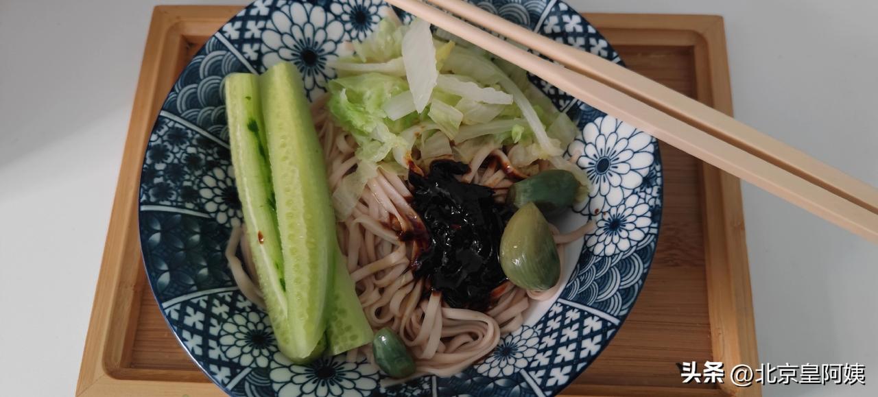 窗外银白世界，屋内热气蒸腾，老伴养的冬虫欢叫。老两口围坐一桌，炸酱面的香气混着腊