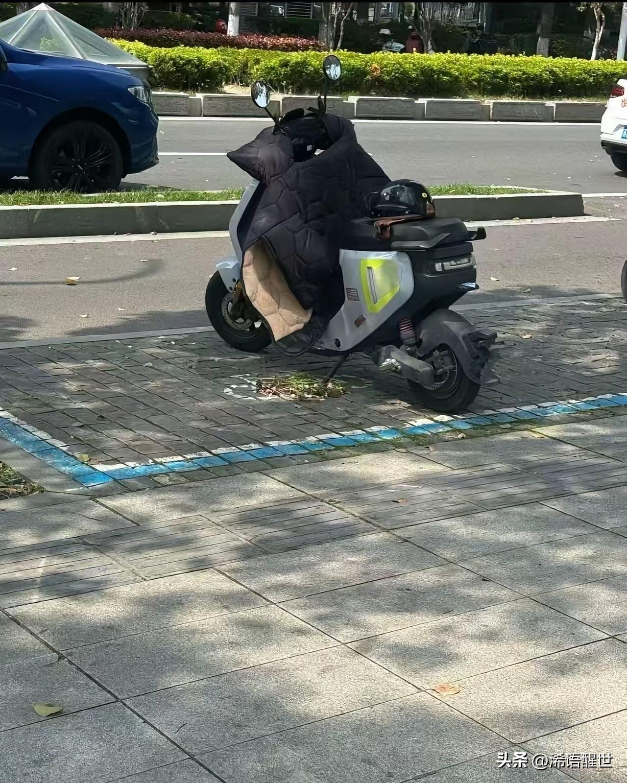 有苏州网友在新闻大厦附近，看到张老师的电动车还孤零零停在路边，车上还放着个头盔。