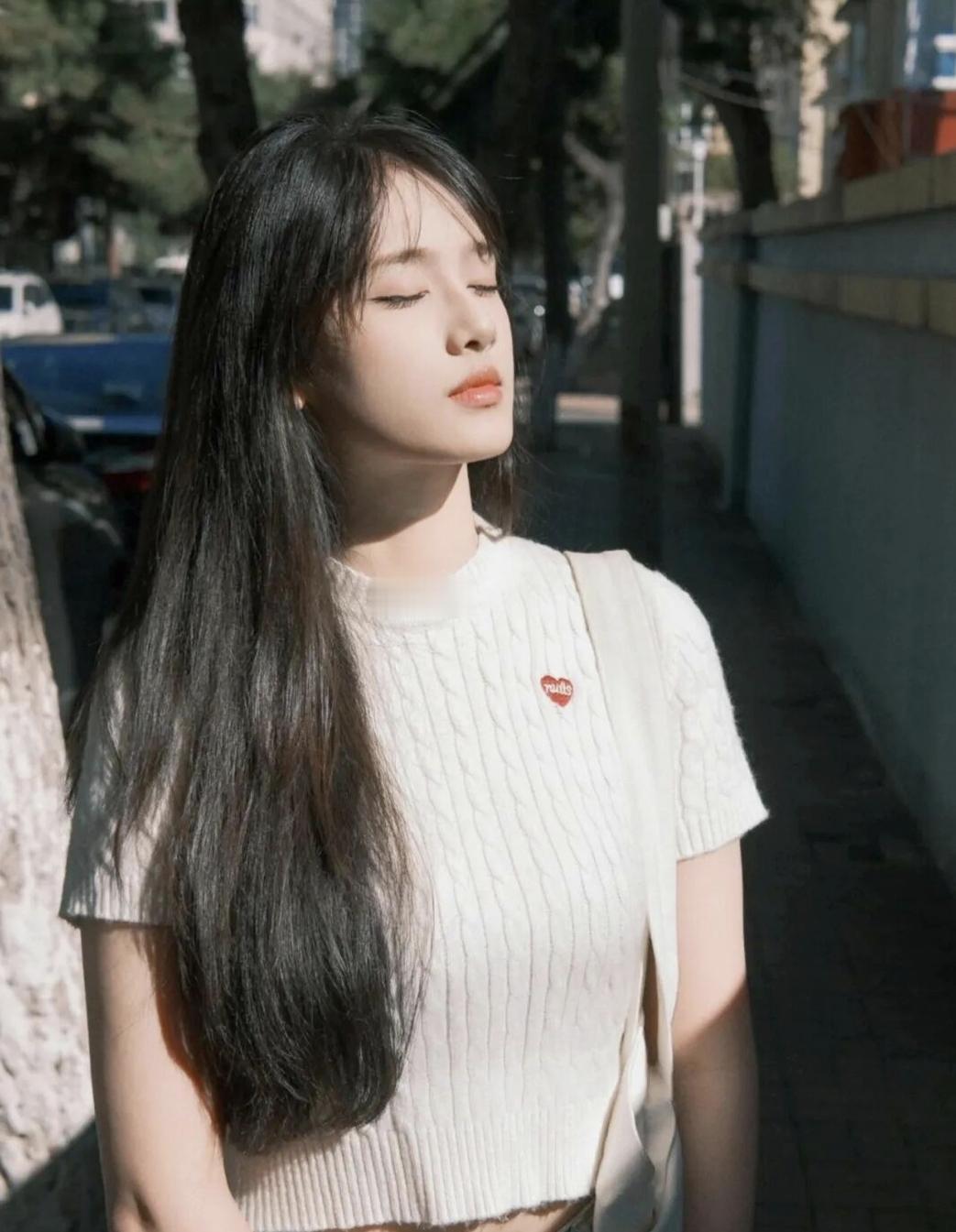 阳光下的温柔少女，微闭双眼，享受宁静时光。