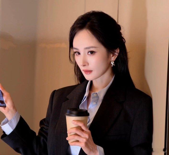 杨幂柔光与山野杨幂定格纯粹底色西装造型里的杨幂拿着咖啡看向镜头，那种自信从容的状