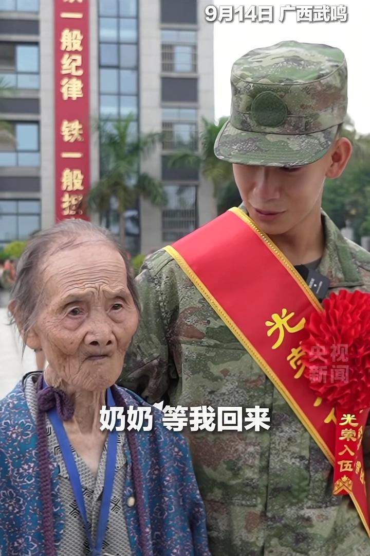 看哭了。广西武鸣，一位97岁的奶奶赶来送孙子入伍，戴着绶带，穿着迷彩服的小伙子红