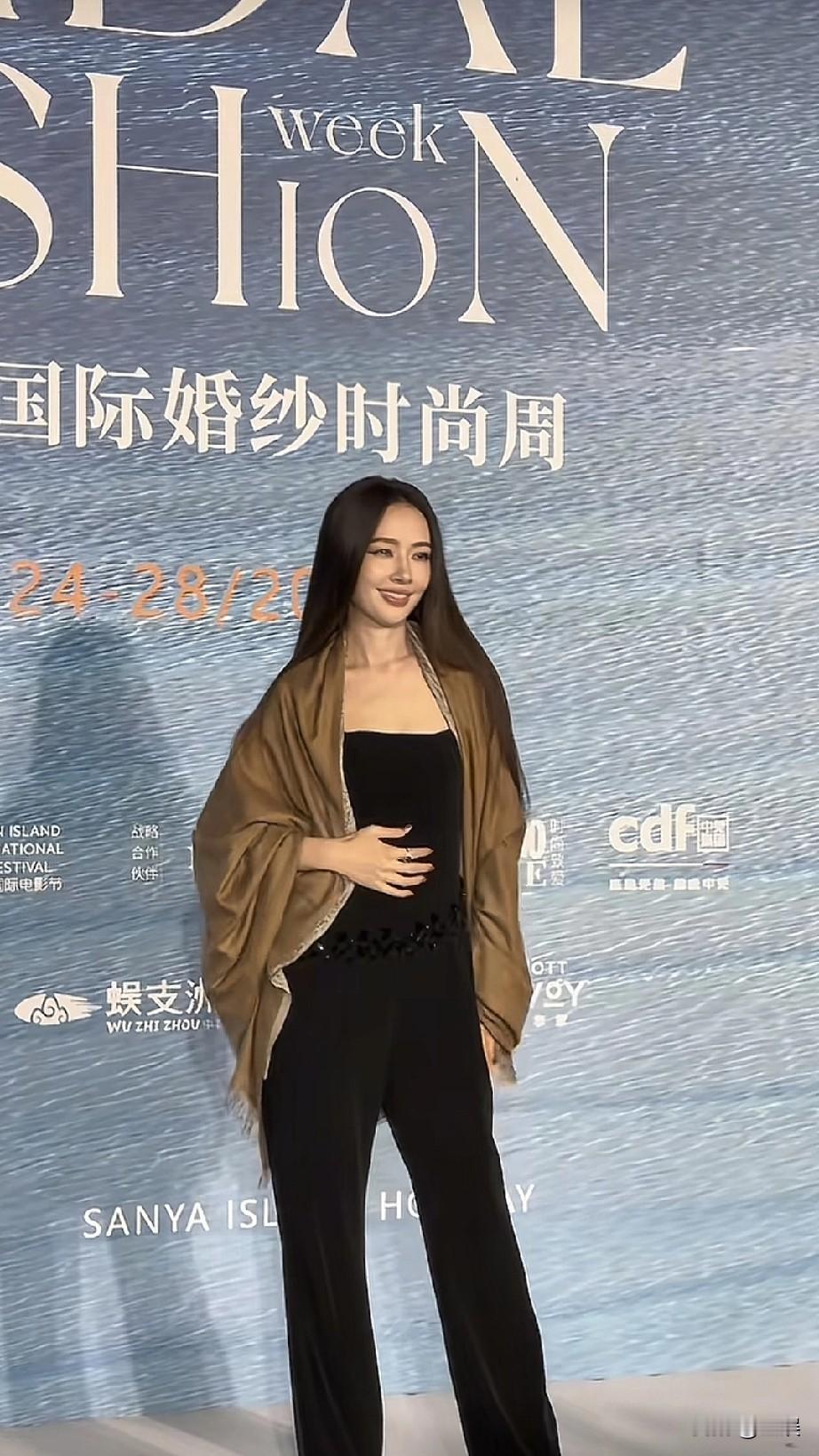 在国际婚纱时尚周的活动现场，郭碧婷以一袭黑色抹胸连体裤搭配棕色披肩亮相，长发自然