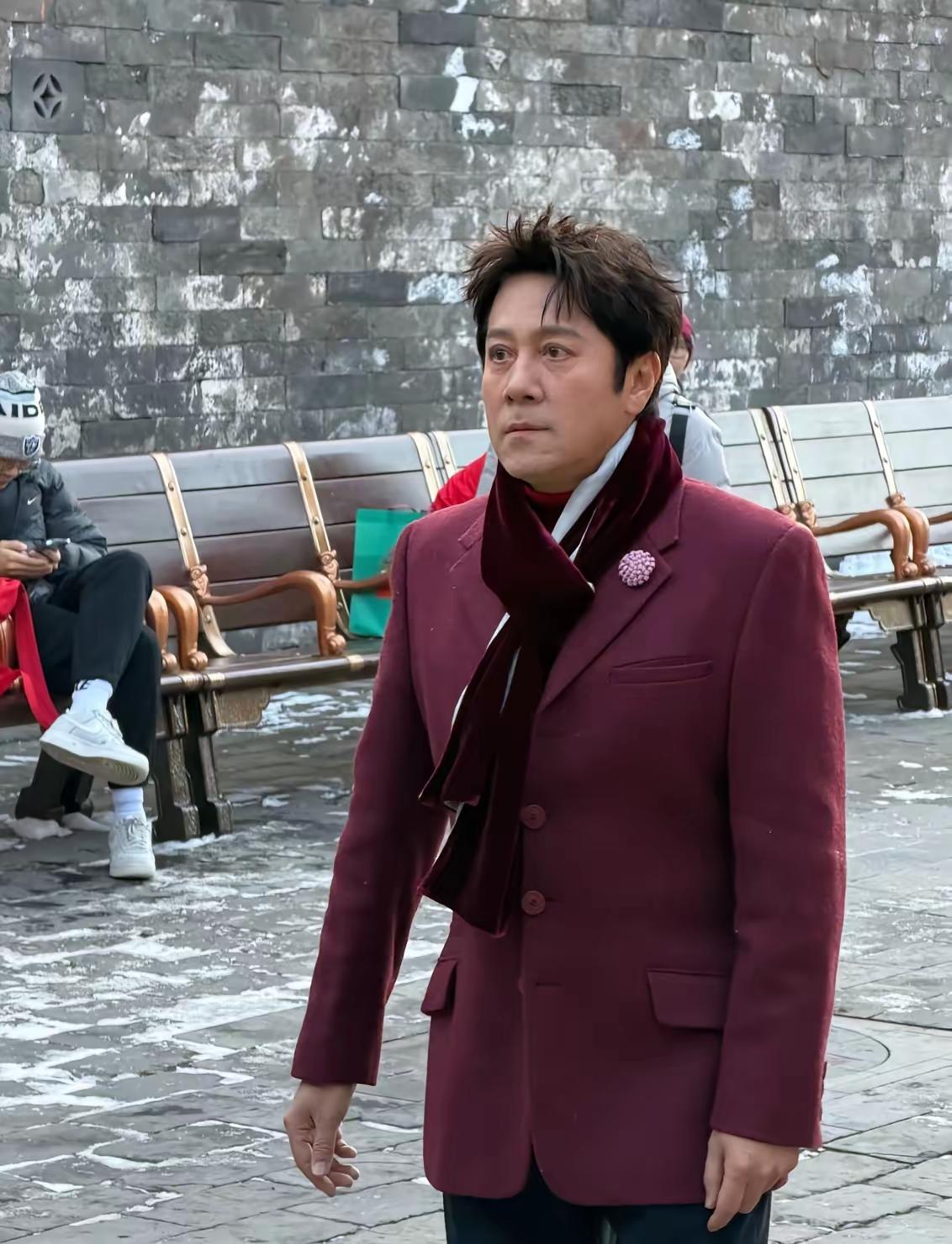 镜头中身着酒红色西装、围着几乎同色系围巾的蔡国庆发型稍显凌乱，眉毛清新疏朗，鼻挺