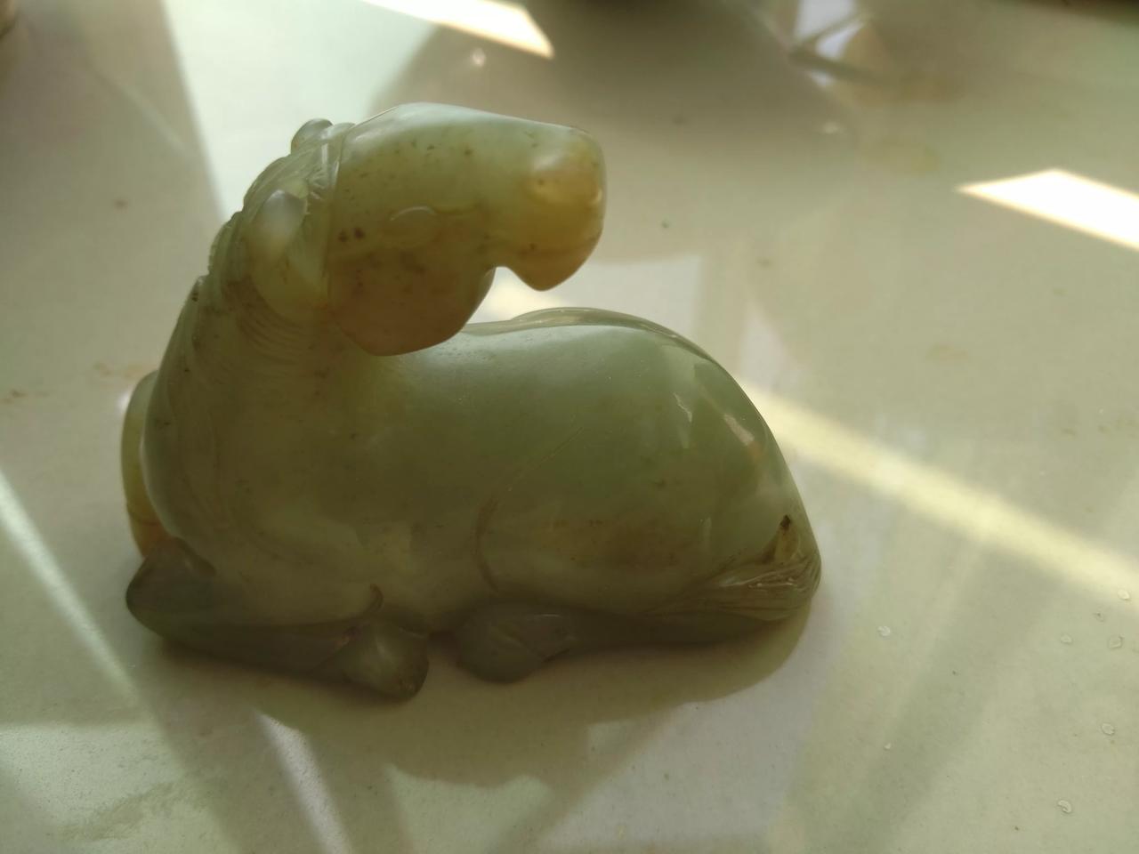 和田青玉卧马，重两百多克，有轻微沁色，有冰裂纹。雕刻生动形象，尤其是头部雕刻写实