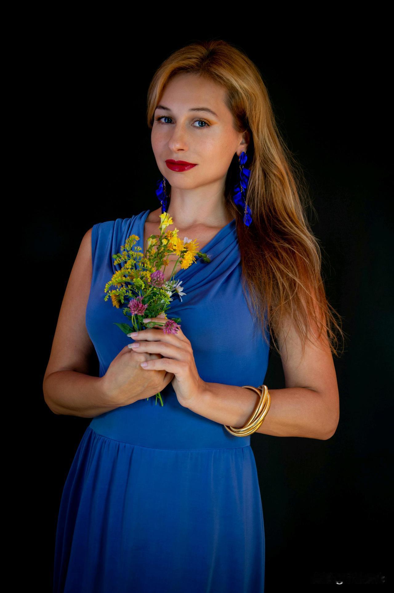 蓝衣美人捧花枝，金镯映辉如月明。