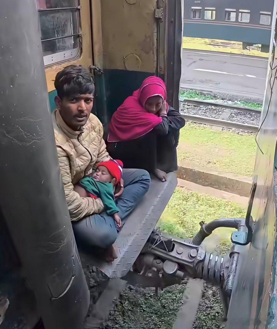 一个印度贫困家庭因买不起车票，只能坐在车厢间的连接处。穷的连鞋也没有，虽不安全，