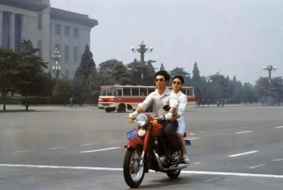 80年代，北京长安街上，一个年轻小伙开着新买的摩托车载着一年轻女子，非常的拉风。