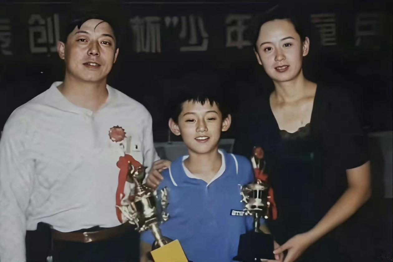 90年代，少年乒乓球赛事领奖现场。张继科小小年纪就拿到了奖杯，父亲张传铭本身也是