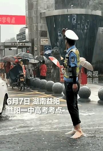 一场突来的暴雨浇在高考考点外。

执勤的辅警没有躲，他脱掉鞋袜踩进水里，笔直站着