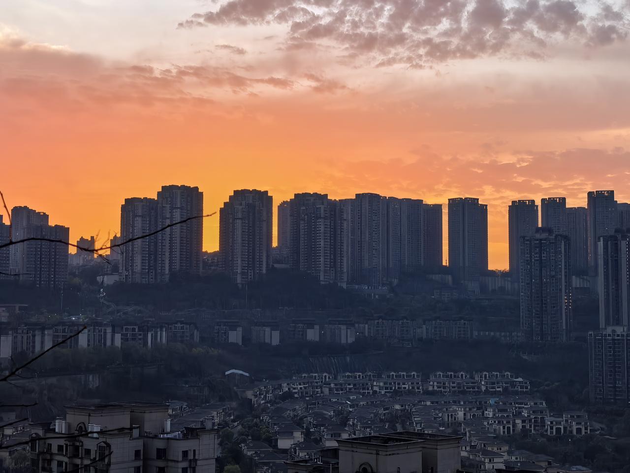 城市在暮色中沉静如墨，天边却燃起一缕橙红的光，像未冷却的熔金，缓缓漫过楼群的轮廓