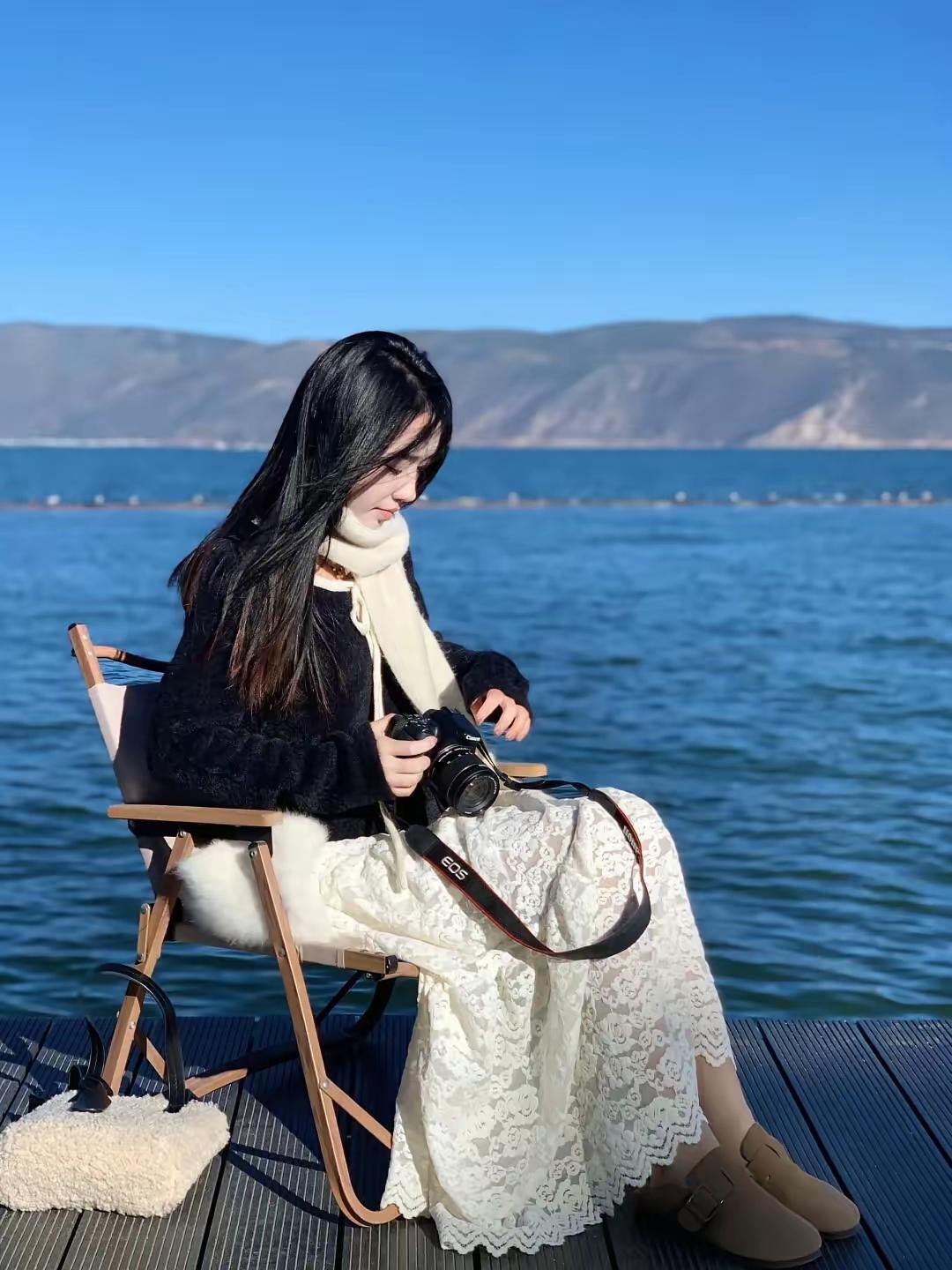 海边拍照的少女，手持相机，享受宁静时光。