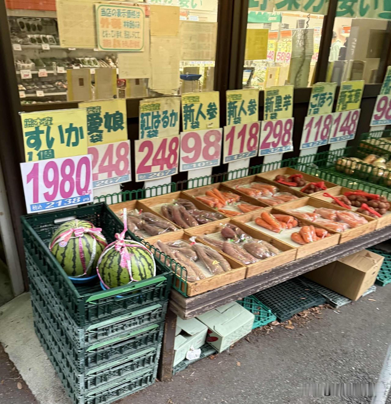日本的路边小菜店。
西瓜、红薯、胡萝卜等的价格。
红色大字标注的价格，是不含税的