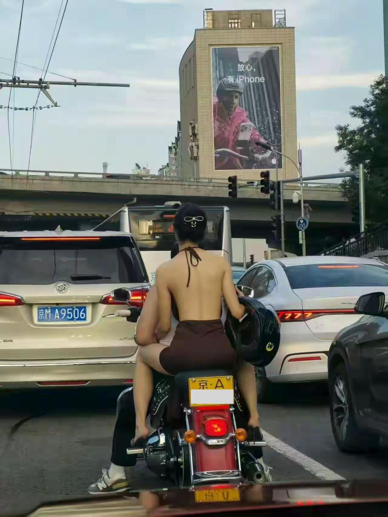 这位美女还真敢出门。可惜的是，委屈了前面开电动车的小阿哥了。