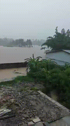 暴雨引发洪水汹涌来袭，浑浊的大水漫过村庄，房屋被浊水围困，遍地散落着洪水冲来的杂