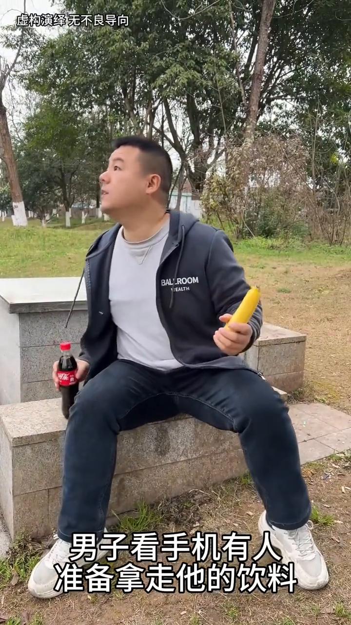 男子看手机有人去拿他的饮料，下一秒他的手机被换成香蕉了。
男子看手机有人准备拿走