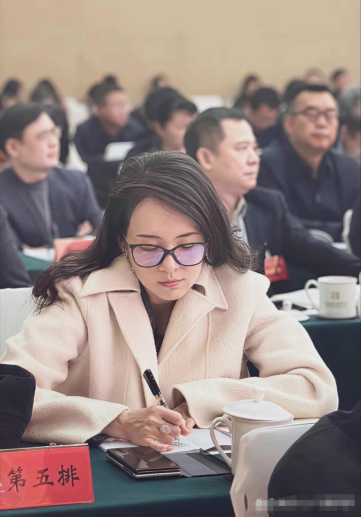 章子怡参加会议照，照片中，素颜出镜的她留着披肩发，戴着眼镜，穿一件米白色的简约大