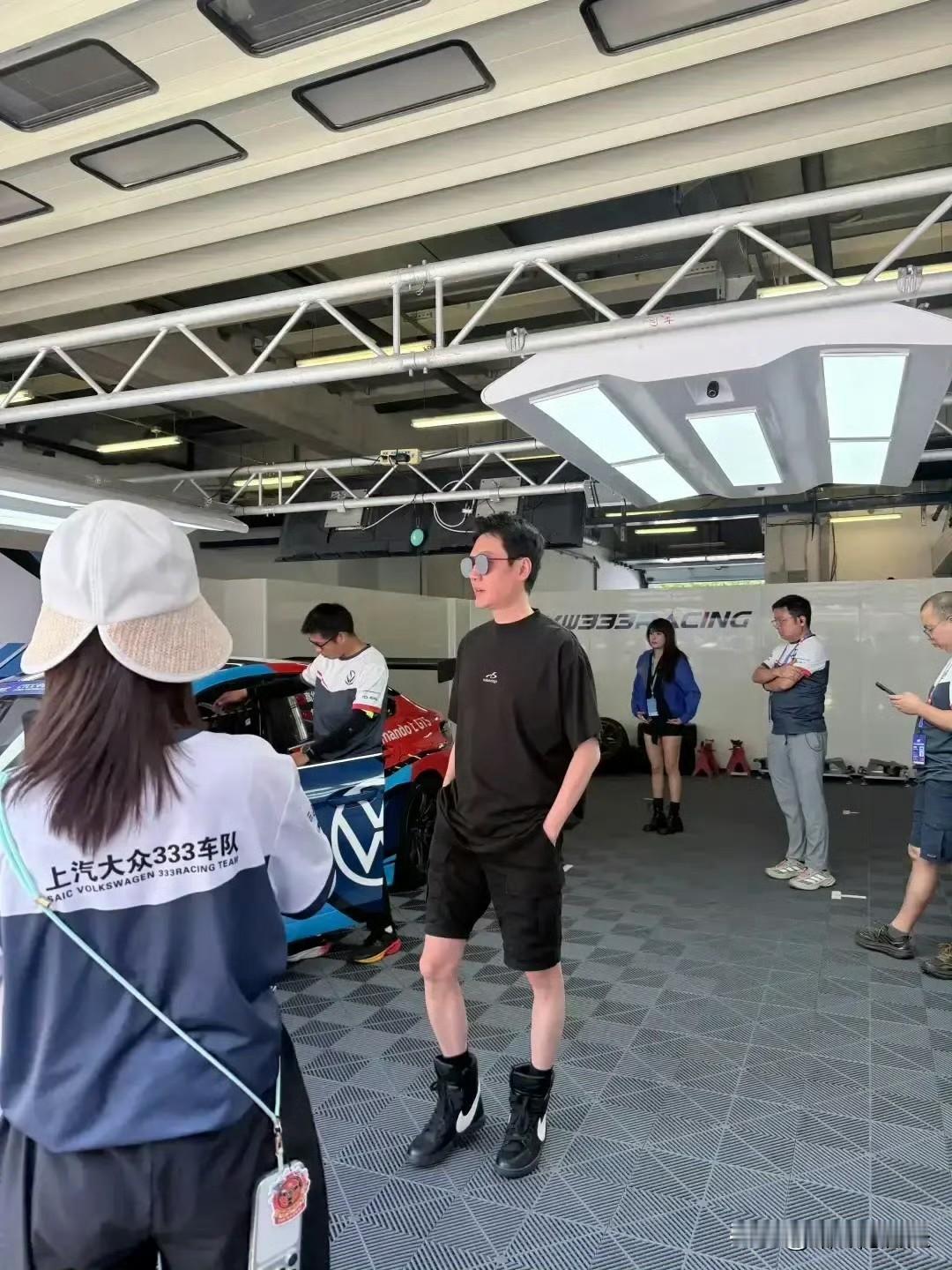 47岁冯绍峰在上海看F1赛车比赛，被媒体拍到他穿了件黑色T恤配短裤，脚上还蹬了双