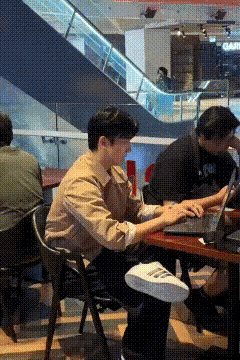 穿搭得体的帅哥商场休闲区内，用笔记本电脑查询着资料，当本人用手从脑后摘下茂密的发