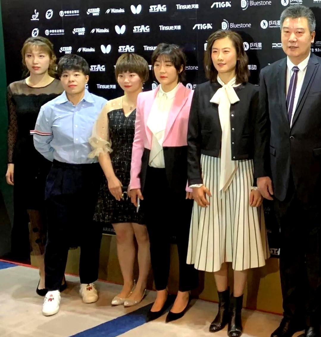 5位国乒女球员与教练盛装同框：

李隼西装革履，高大修伟；丁宁秀发垂肩，双腮染赤