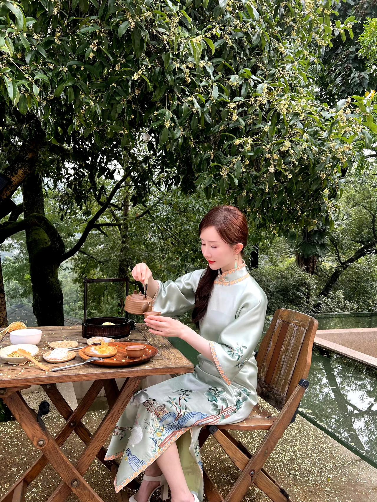 金秋十月，桂花飘香。穿着中式旗袍裙坐在桂花树下的她优雅从容的喝着茶，吃着点心。这