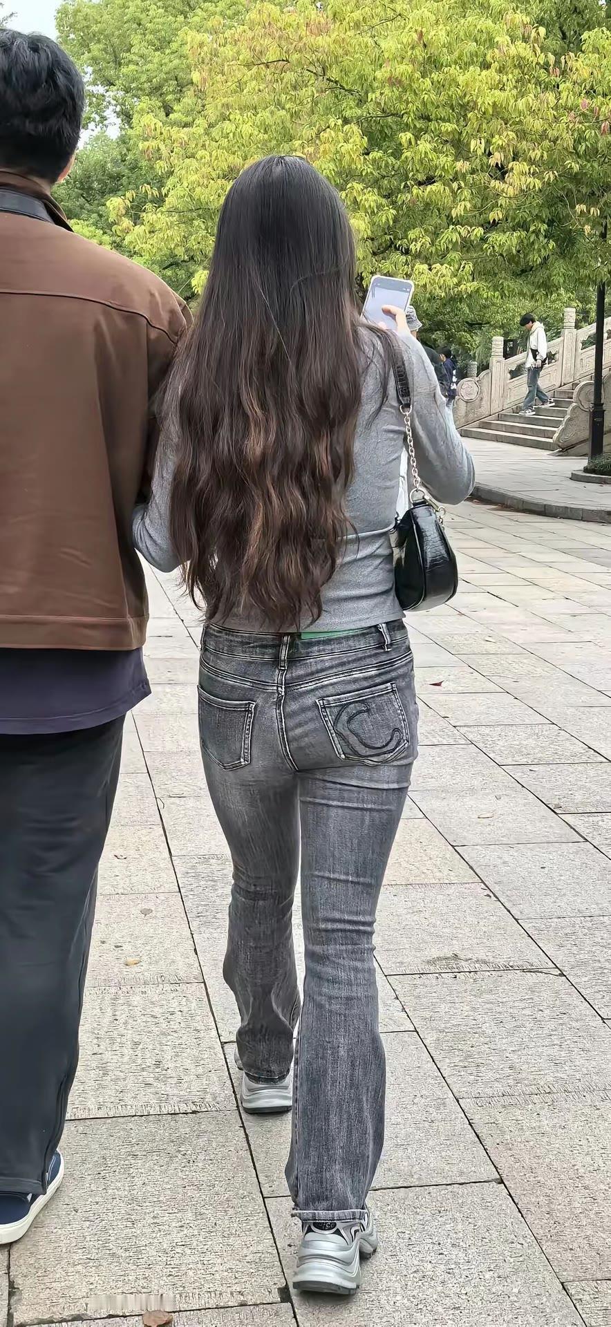 两个人在公园里散步，女士在看手机。