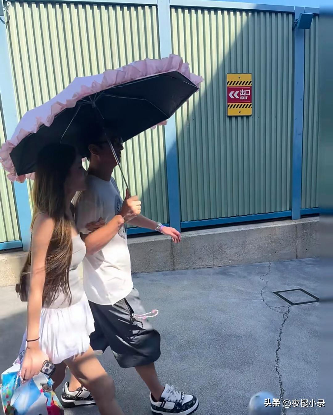 王思聪和他女友懒懒在日本大阪逛街，王思聪撑着遮阳伞，他女友亲密地挽着他的手，那氛