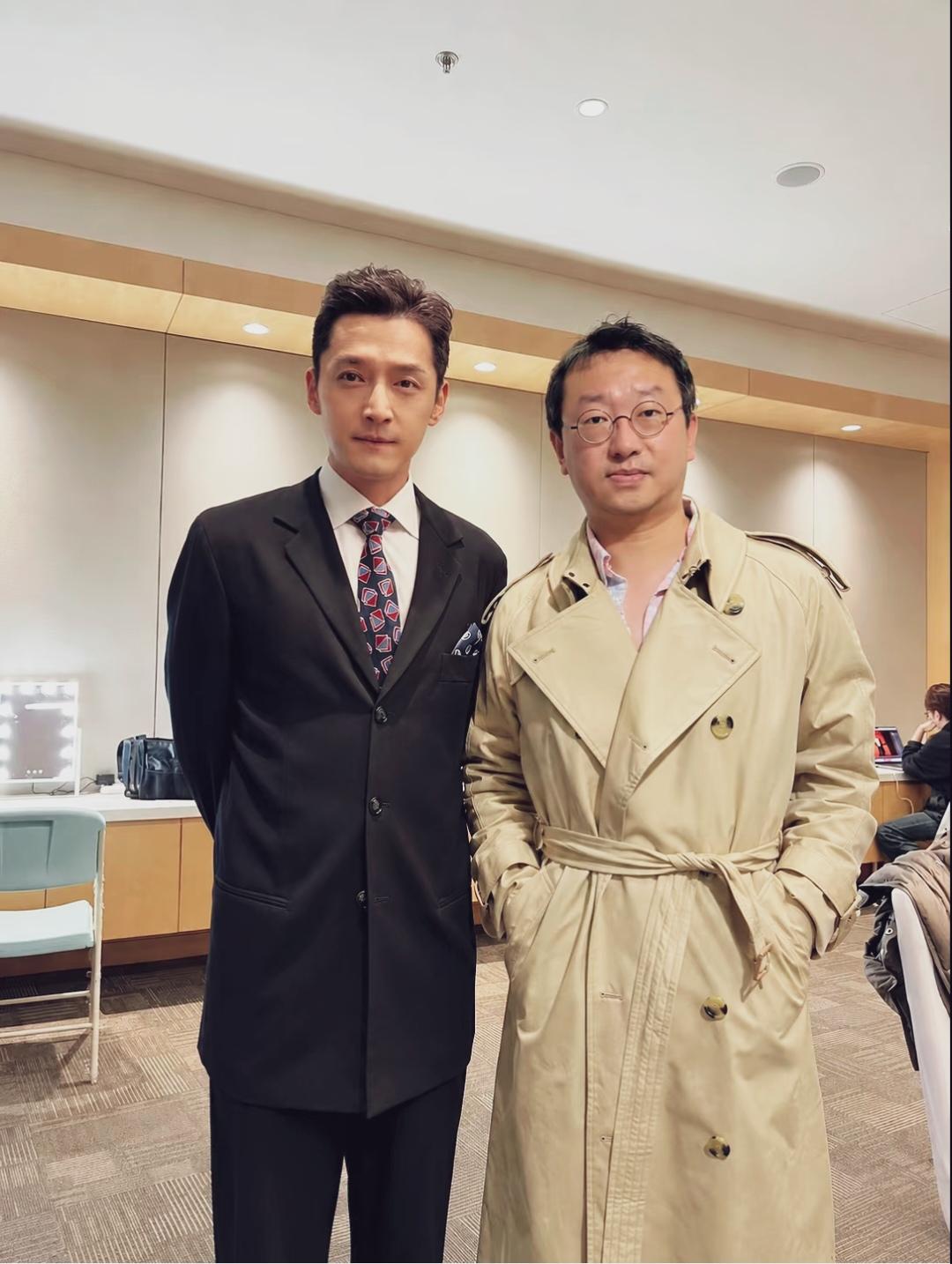 胡歌一身剪裁合身的黑色西装，造型非常正式、干练利落。他面带微笑，由于车祸导致双眼