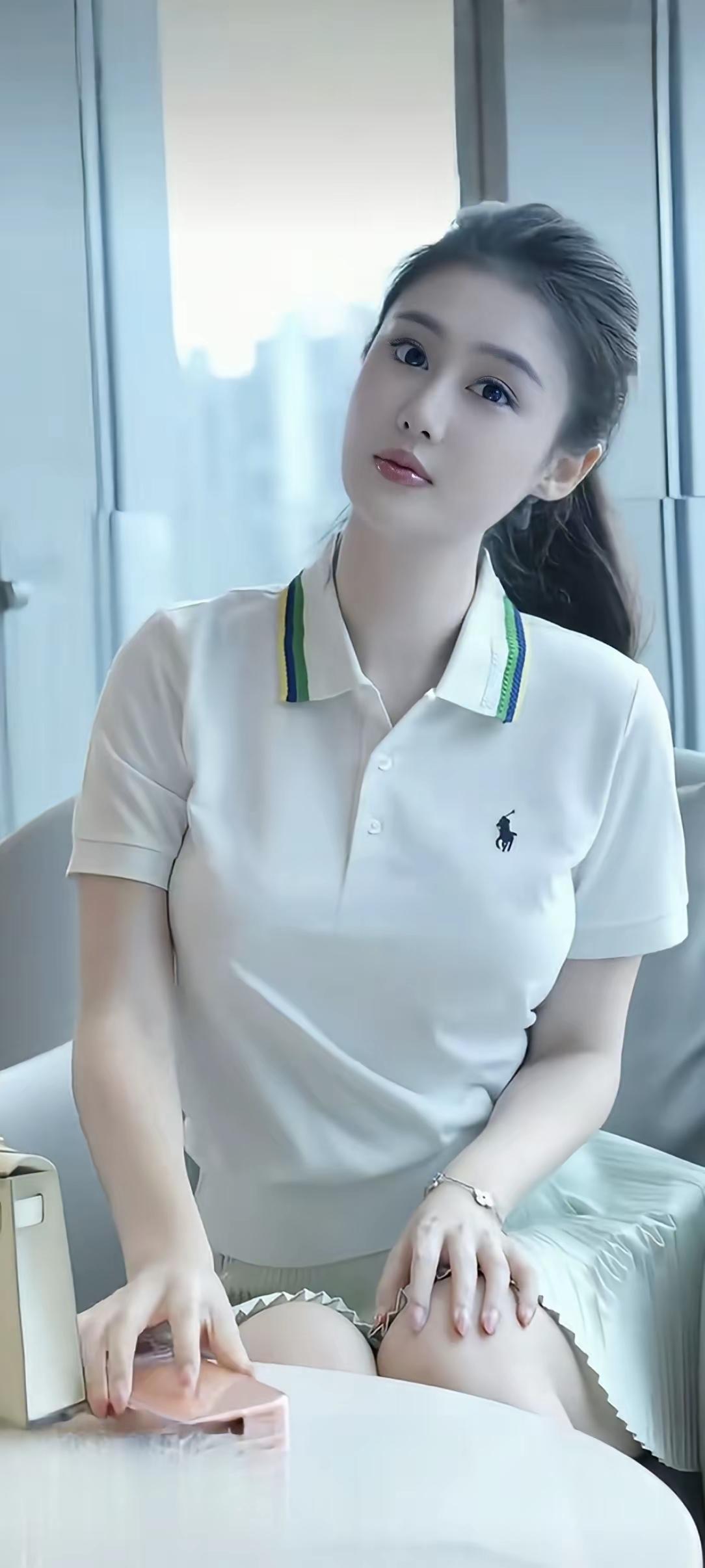 妹子穿着白Polo，坐在窗边。