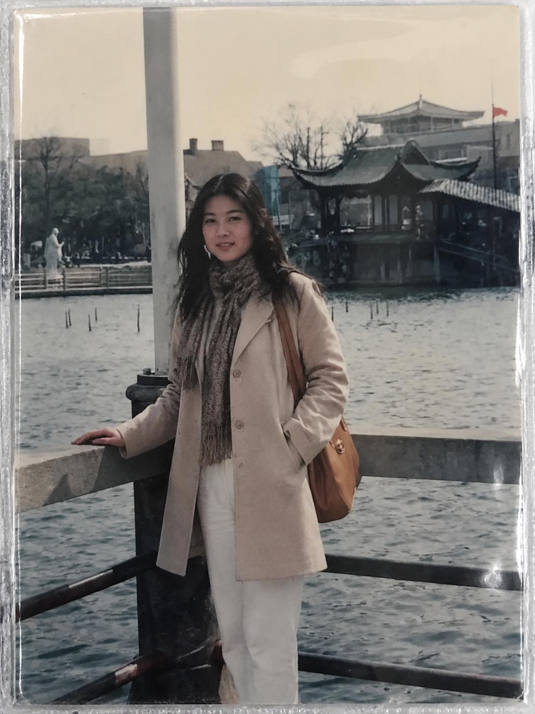 这张照片是妈妈20多岁的时候在安徽镜湖公园拍的，一套简单的搭配，米色大衣和白色裤