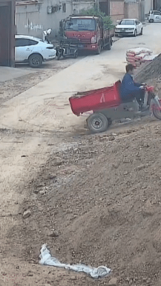 男子驾驶电动三轮车上坡。
结果由于重心不稳突然发生了翻车事故！
在翻车的瞬间险些