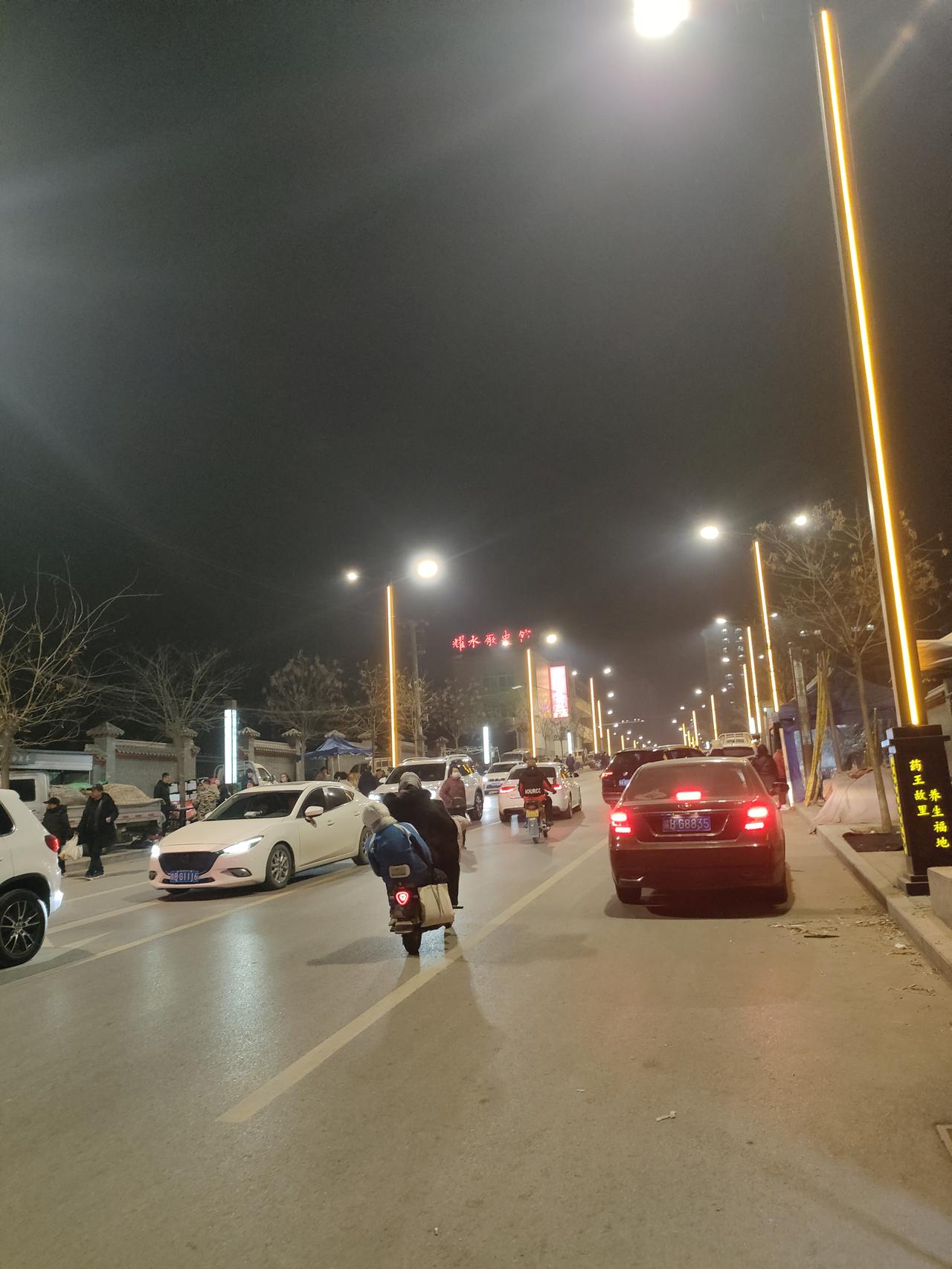 路灯把夜色烫出金边，车流与人影在街心漫成河流，每个赶路的灵魂都揣着暖黄的梦。
?