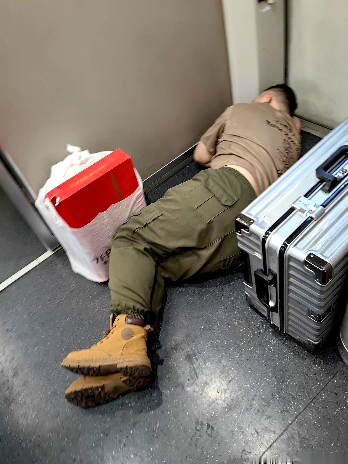 高铁车厢连接处，一个小伙子就那么直挺挺地躺下了。
旁边就是厕所，人来人往，一双双