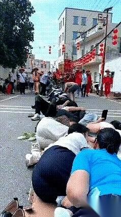 一大群人，齐刷刷趴在一条土路上。
但你凑近了看，没一个愁眉苦脸的，反倒个个咧着嘴