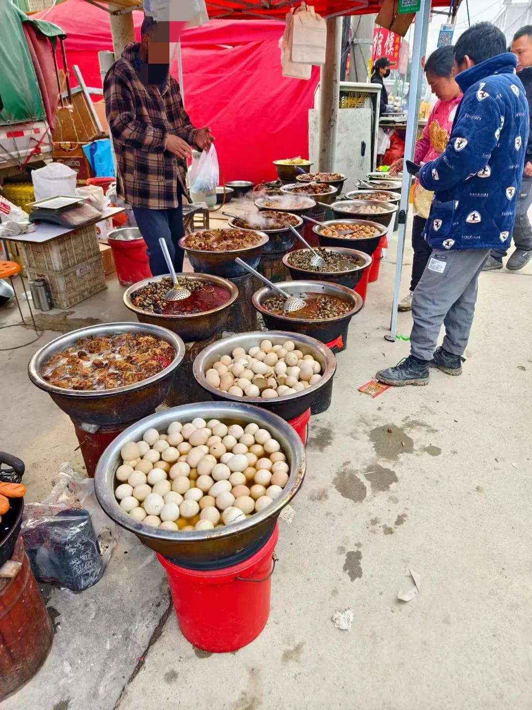 这就是乡村庙会上的地摊美食，毛蛋（即没孵化出小鸡的鸡蛋），麻辣鸡头，螺蛳，狗肉，