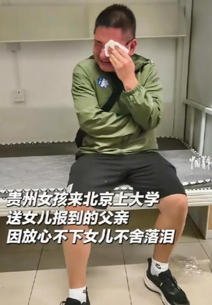 贵州一父亲送女儿来北京上大学，给女儿报到完后，坐在女儿宿舍的架子床上用纸巾一直抹