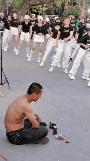 傍晚时分，一位光膀子的大哥一个人坐在地上，他一边吃着卤蛋一边喝着啤酒。
并且还饶