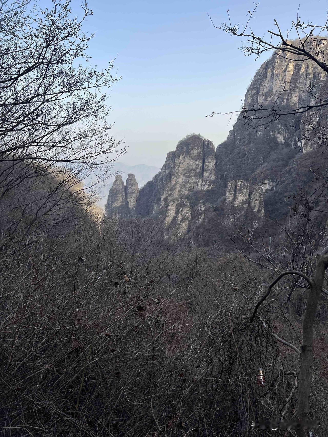 山峦叠嶂，树枝光秃，景色清冷。