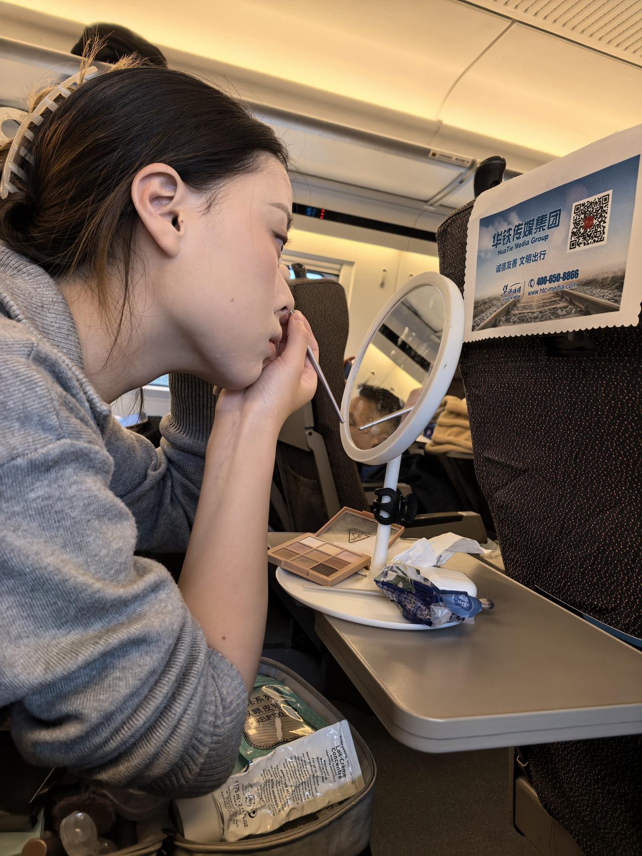 南京到杭州的早班高铁上，一位在高铁上化妆的女青年。
突然想起之前看到一段话：“生