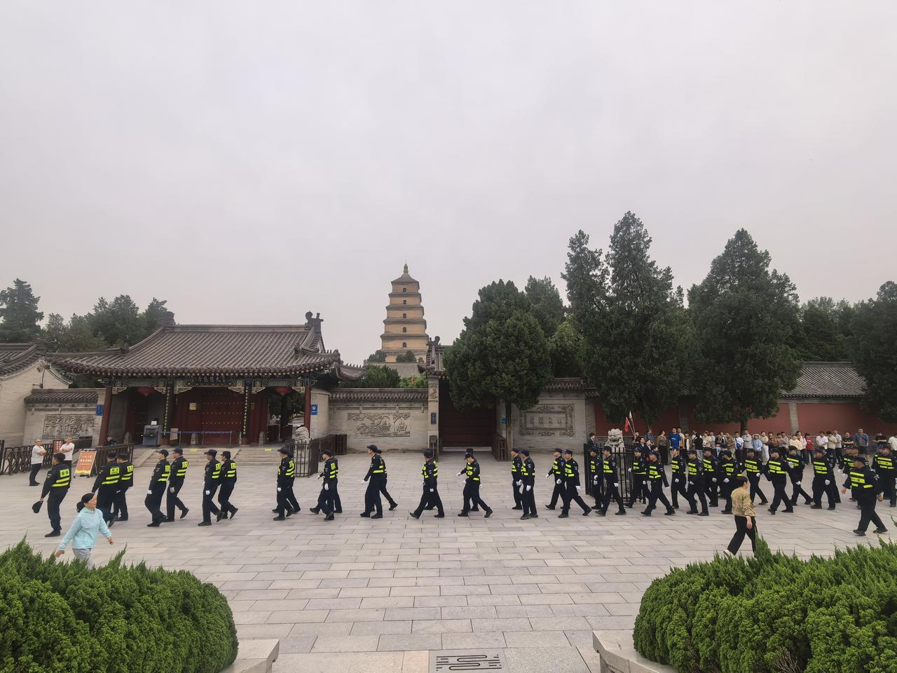 啥情况？一大队保安，从大慈恩寺南门前齐刷刷走过。

统一的制服，还有反光背心。步