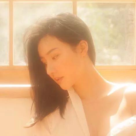 阳光洒满房间，少女在微风中轻闭双眼，享受片刻宁静。