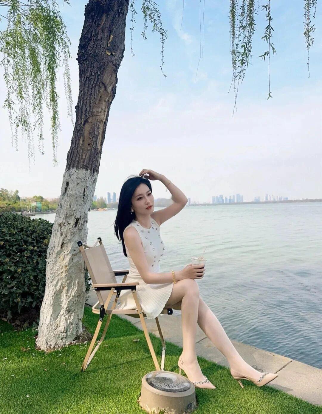 《湖畔的宁静时光》
在温暖的阳光下，一位女性静静地坐在户外的折叠椅上，享受着这难