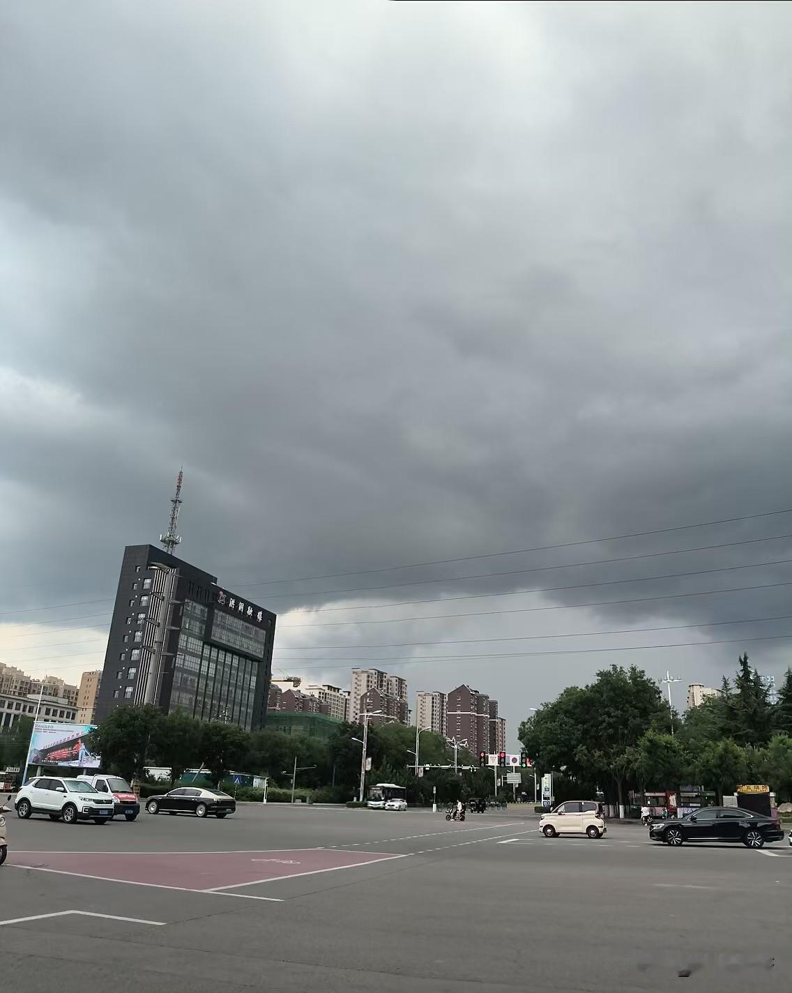 夏日生活打卡季洪洞县城上空乌云滚滚，厚重黑云压向城区。大雨即将来袭，路口车流往来
