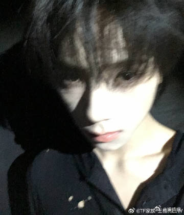 王橹杰病娇系自拍交错光影勾勒少年模样，黑衬衫尽显冷调质感，眼下红色标记形成视觉焦