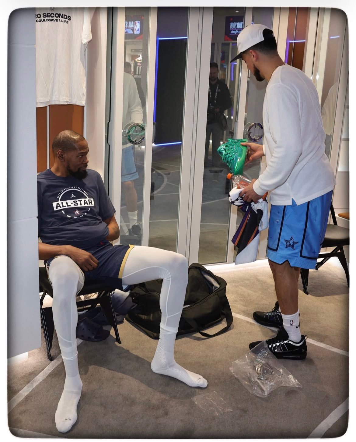 德文·布克在全明星周末期间，端详凯文·杜兰特的「警告标签」主题KD 18战靴 ?