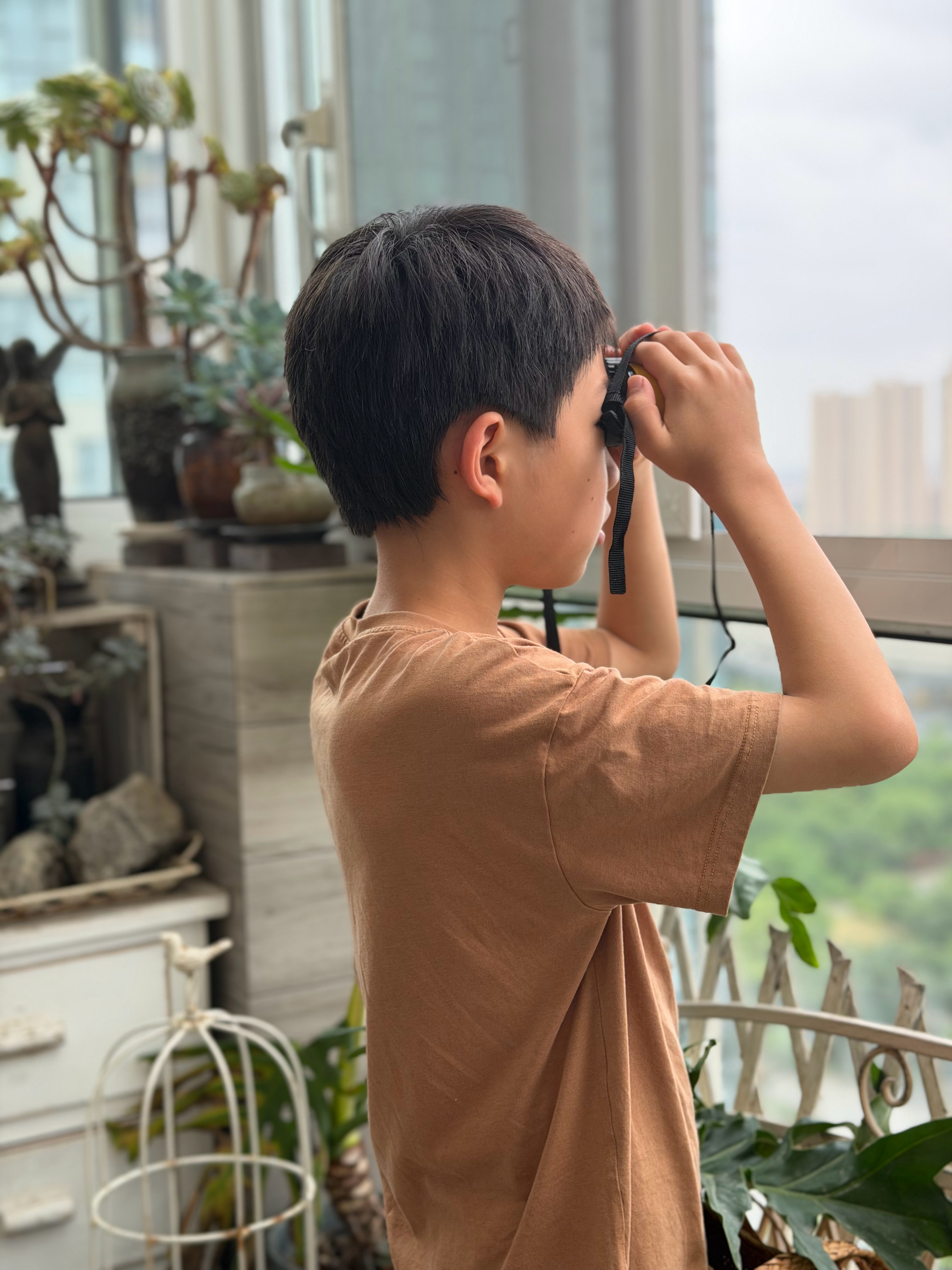 我俩在台风天开着阳台窗在用望远镜看远，真是够无聊了。被他发现远处河对面居然有个穿