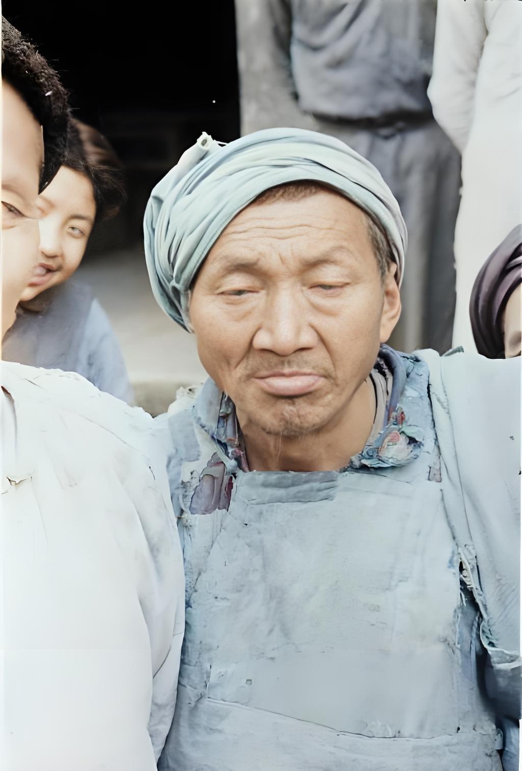 这是1944年拍摄于山西省的男子肖像照。一位男子裹着头巾，身上的粗布衣裳破得不成