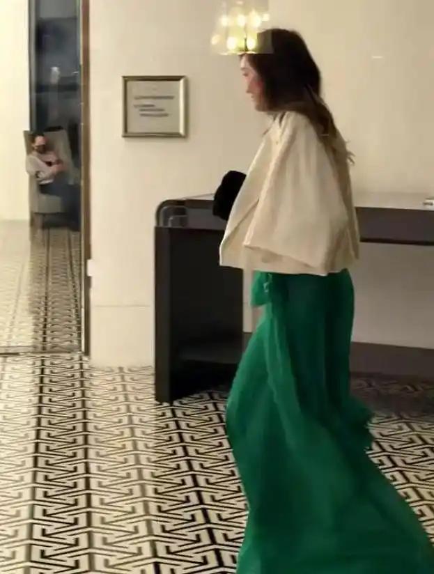 58岁孟广美在香港被偶遇。 墨绿色丝质长裙，白色短外套，手里拎着包，低头看着路面