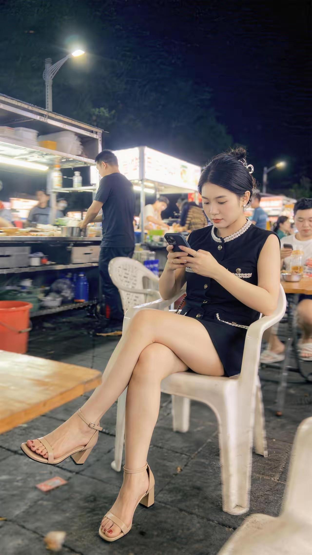 路边摊刷手机的女子。
应该是原图吧，很有生活气息！